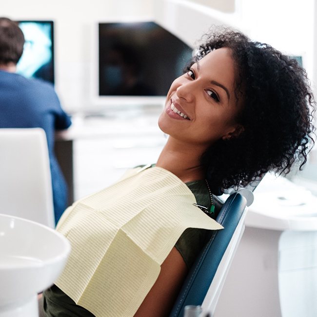 mujer sonriente sentada en el sillón dental